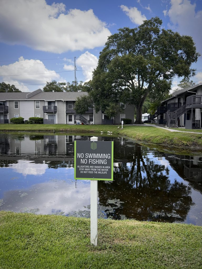 A photo of a warning sign in front of a pond at a condo complex.